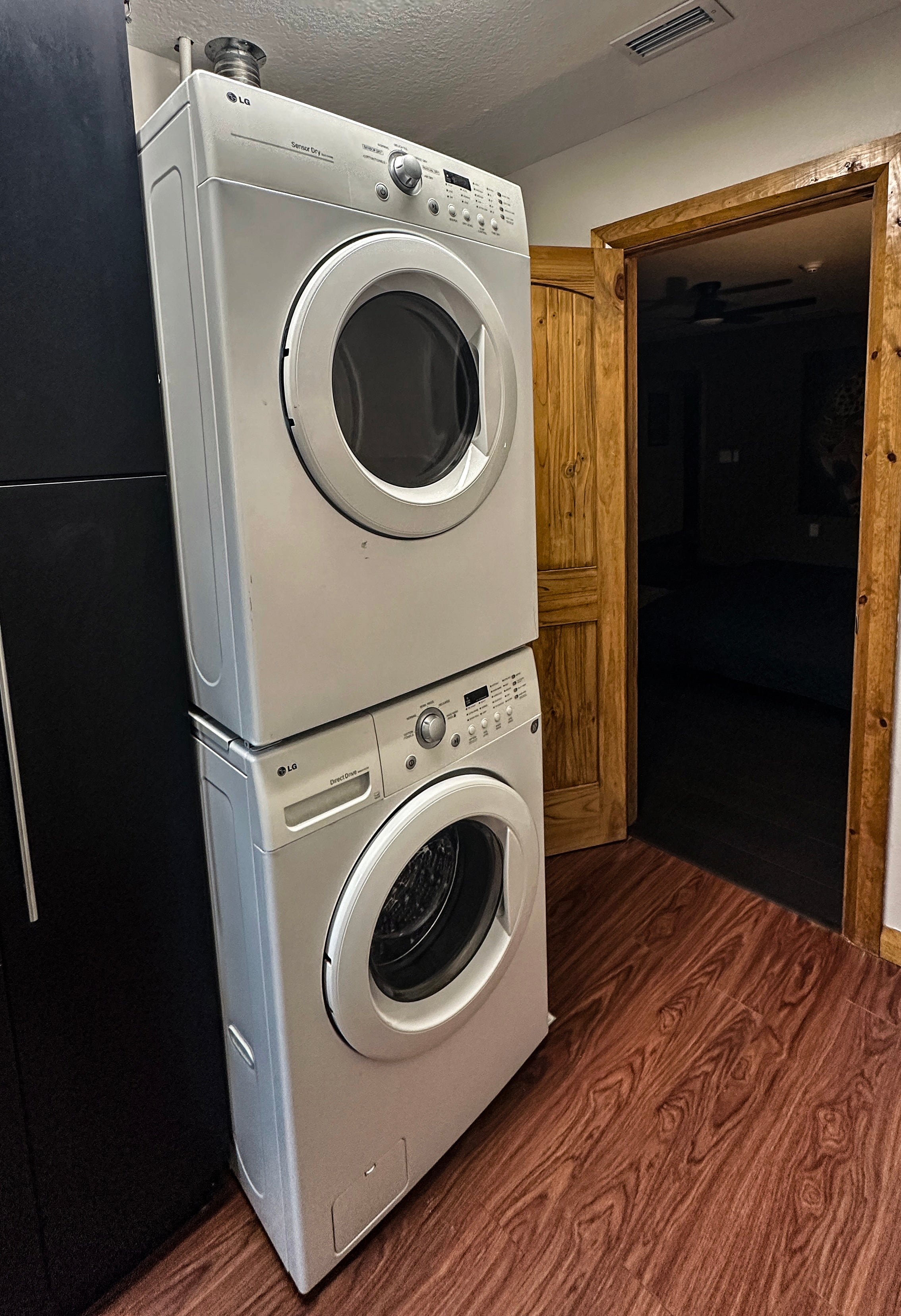 Stacked washer and dryer set against a wooden wall.